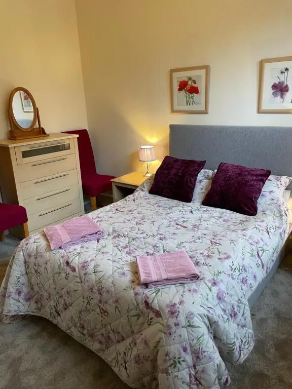 a bedroom with a large bed with purple pillows at Reay Street Apartment in Inverness