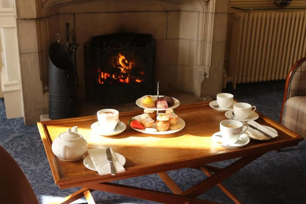 a coffee table with food and cups and a fireplace at Craiglynne Hotel in Grantown on Spey