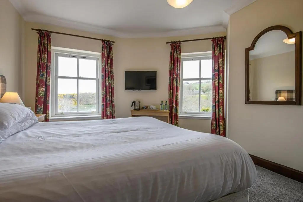 a bedroom with a large bed and two windows at The Bridge Helmsdale in Helmsdale
