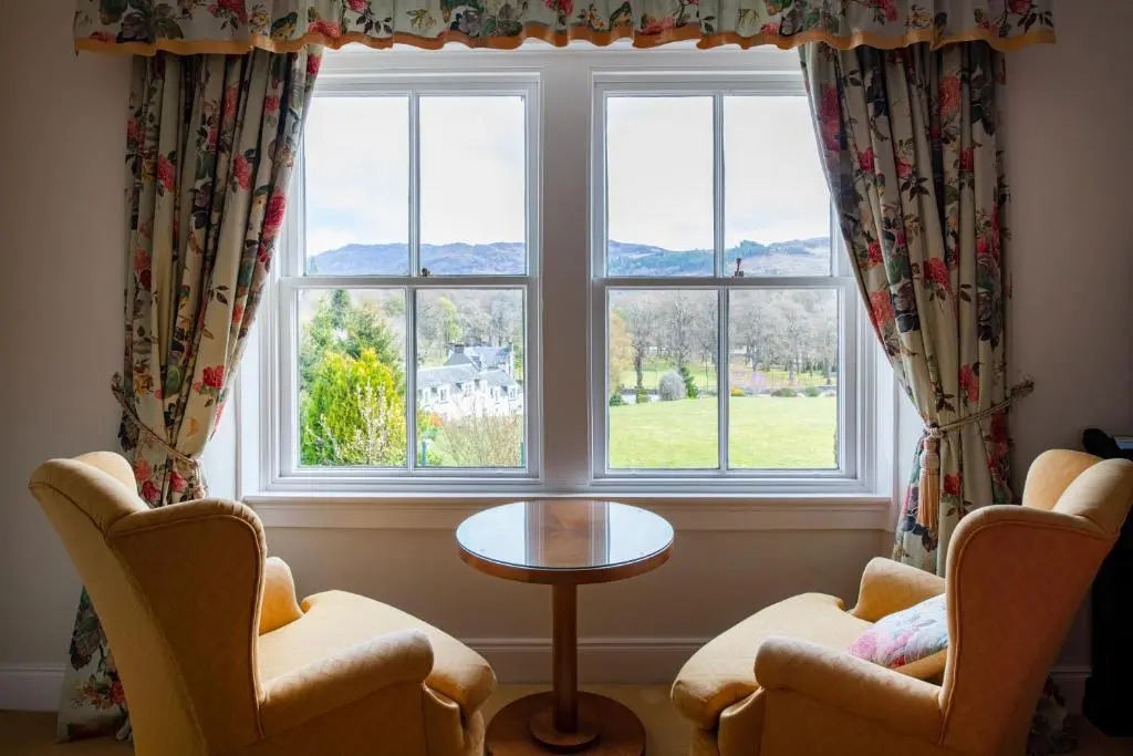 a room with two chairs and a table and a window at The Lovat, Loch Ness in Fort Augustus