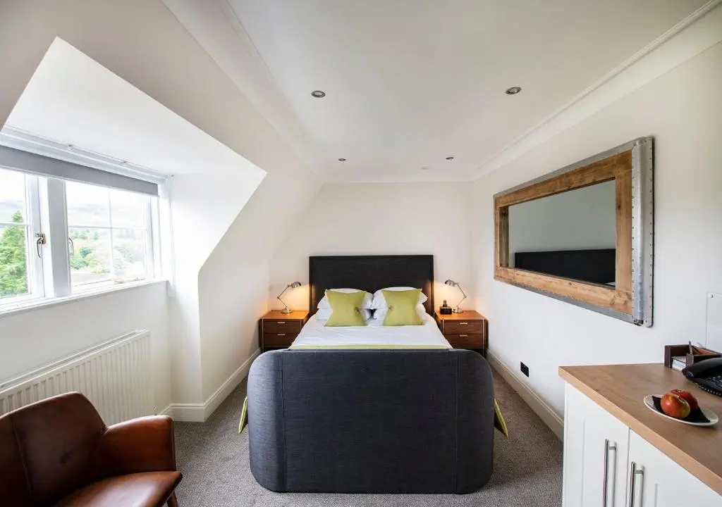 a bedroom with a bed and a mirror on the wall at The Lovat, Loch Ness in Fort Augustus