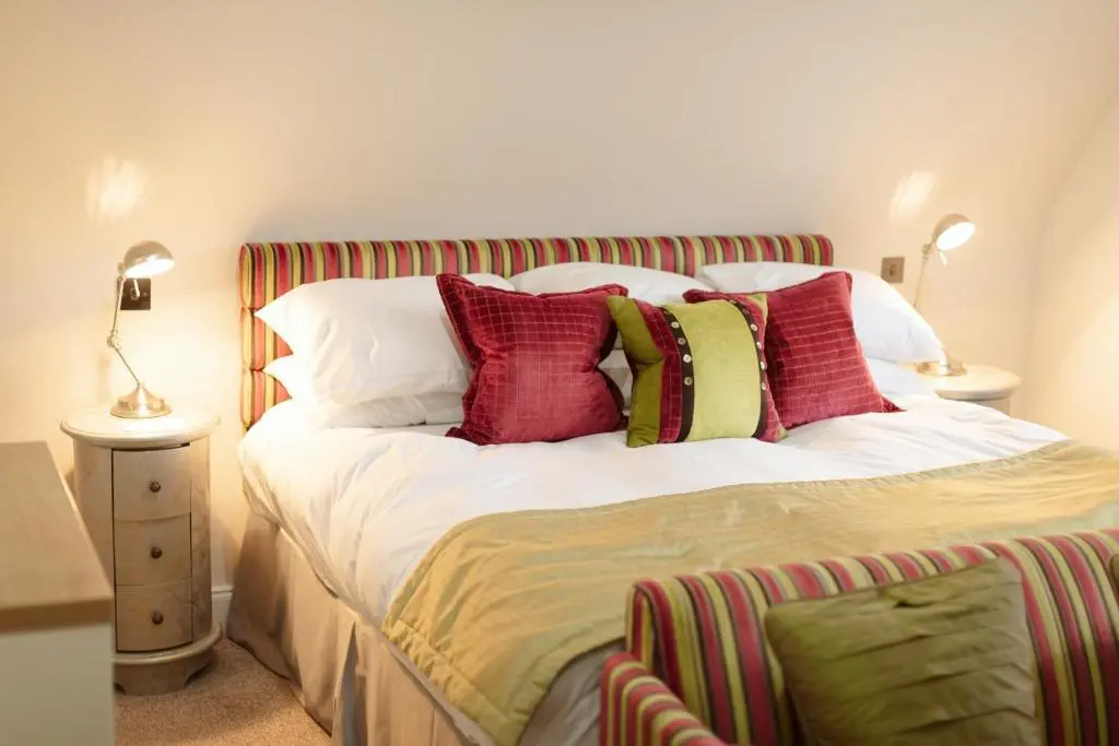 a bedroom with a bed with red and green pillows at The Lovat, Loch Ness in Fort Augustus