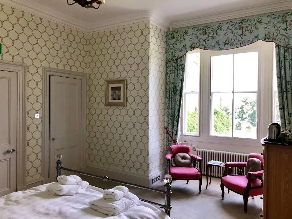 a bedroom with a bed and two chairs and a window at Netherdale House & The Coach House in Turriff