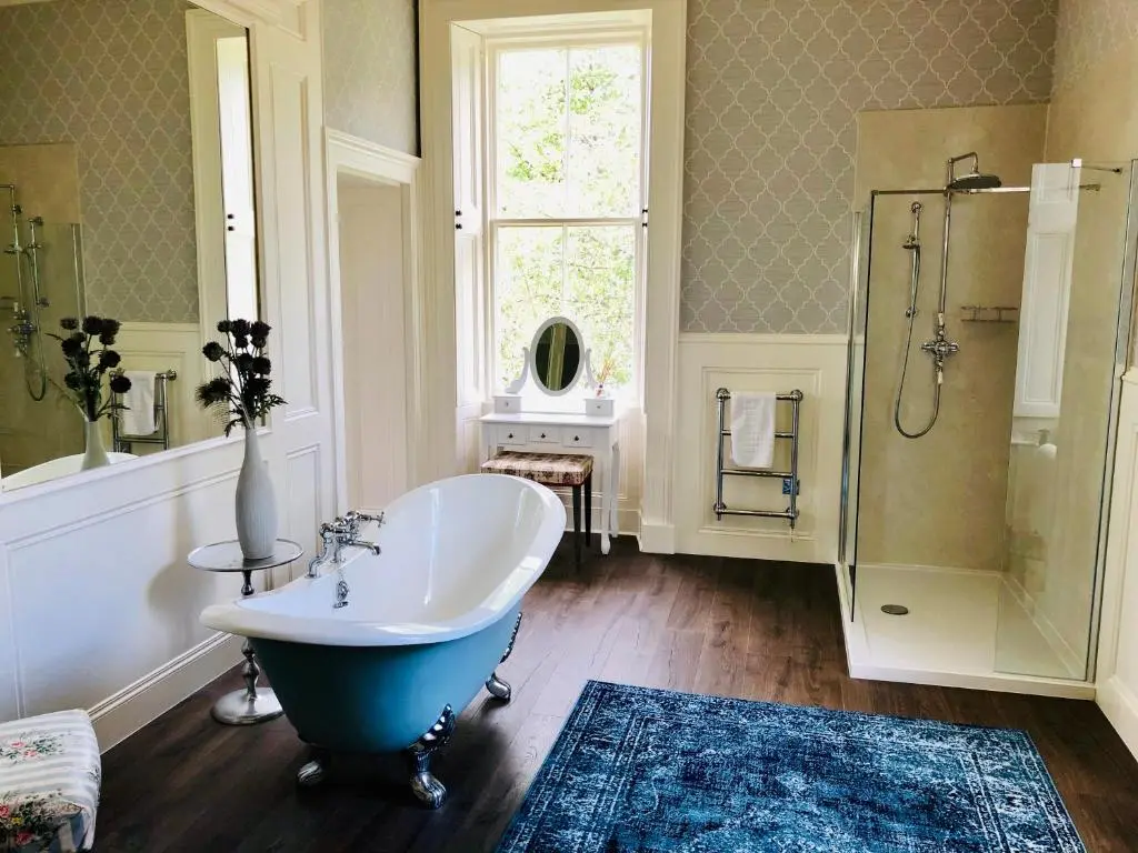 a bathroom with a tub and a shower with a window at Netherdale House & The Coach House in Turriff