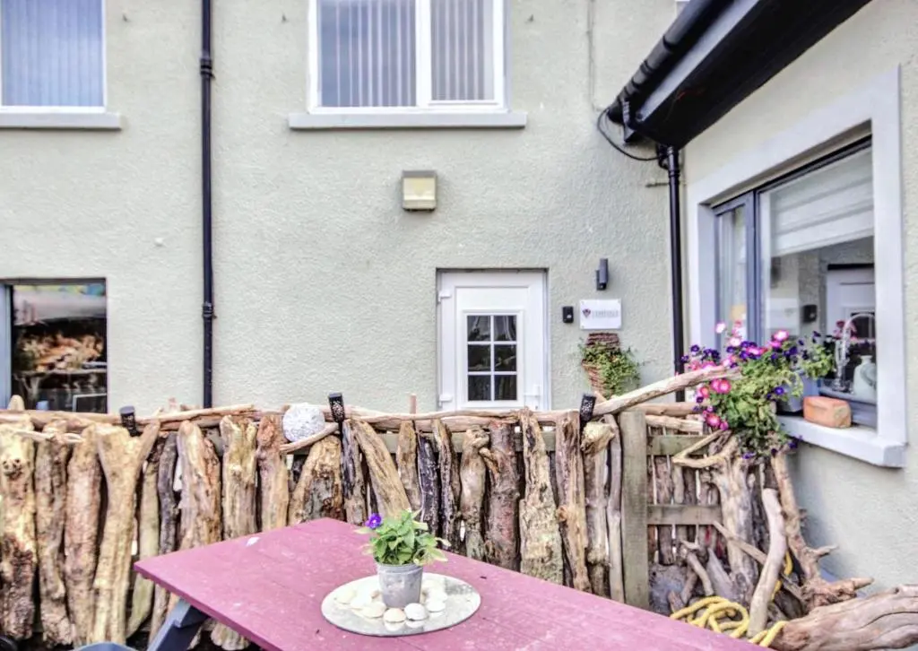 a table in front of a house with a fence at Thistle Apartment Golspie in Golspie