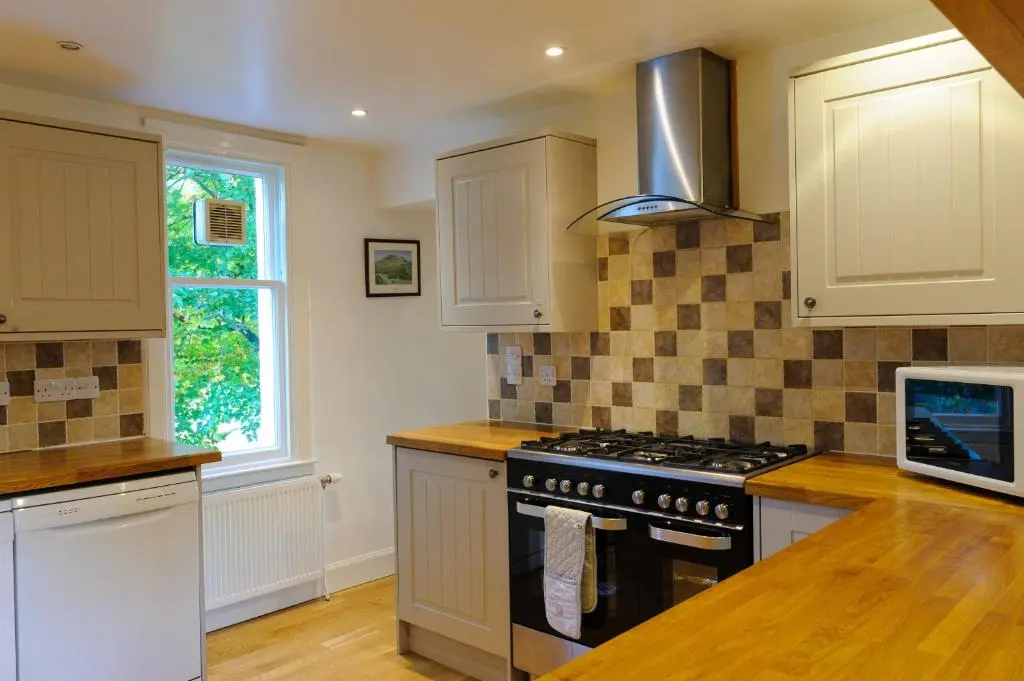 a kitchen with white cabinets and a stove top oven at Alvey House in Newtonmore