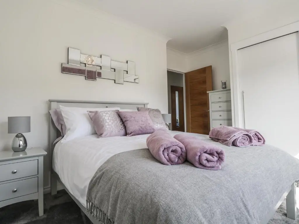 a bedroom with a bed with purple pillows on it at 24 Waters Edge in Banff