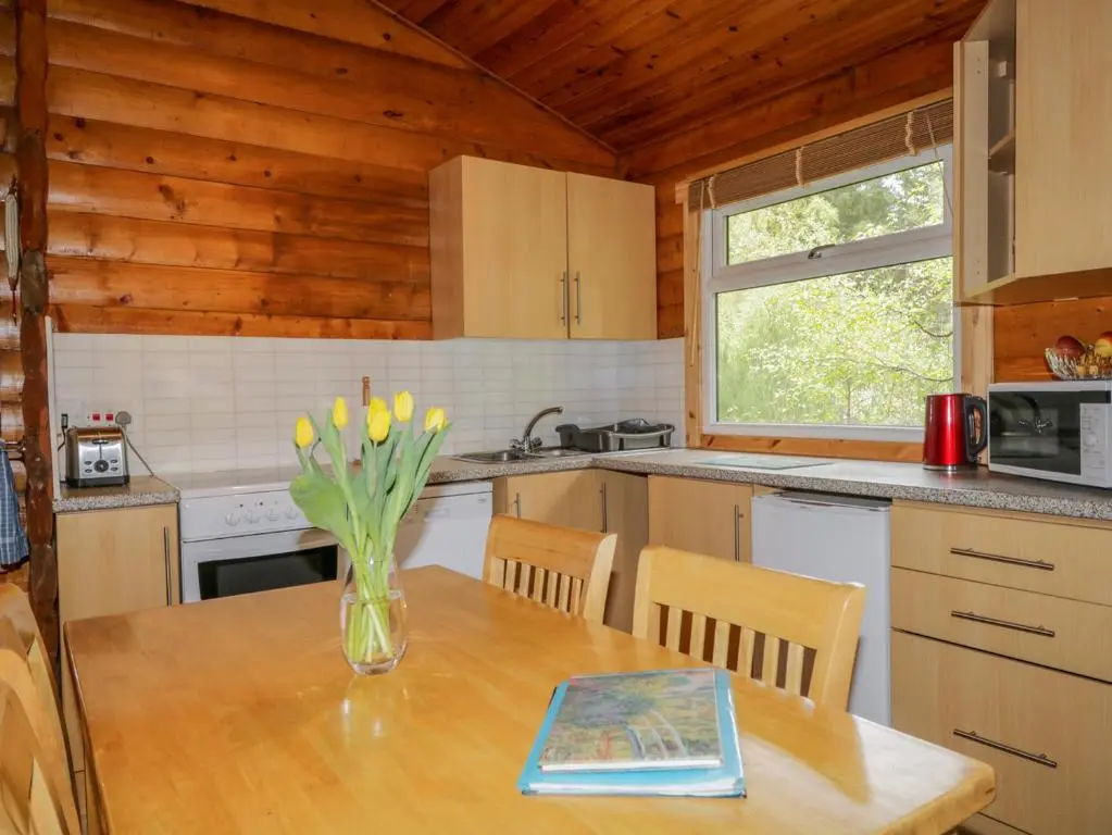 a kitchen with a table with a vase of flowers on it at Eagle Lodge in Strathpeffer