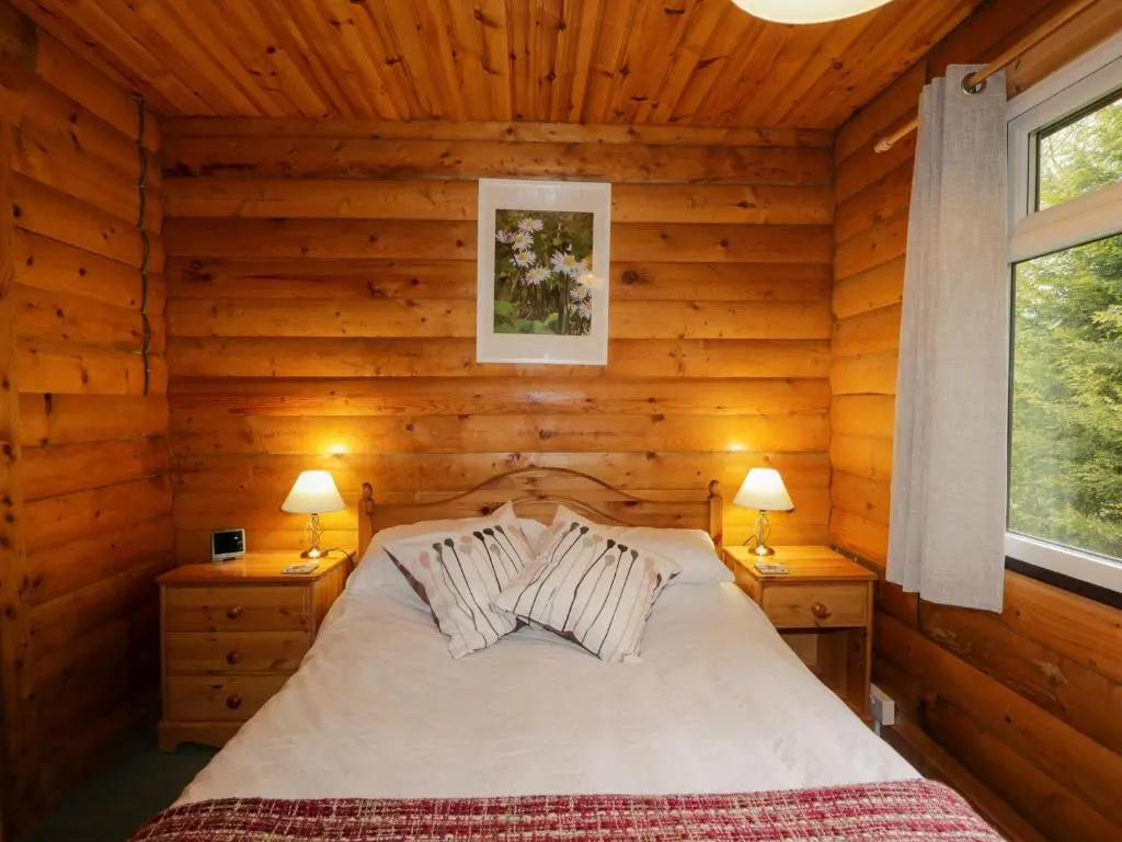 a bedroom with a bed in a log cabin at Eagle Lodge in Strathpeffer