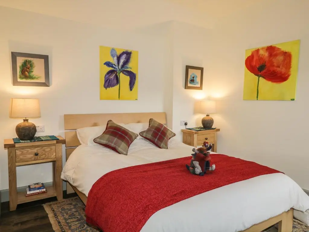 a bedroom with a bed with a teddy bear sitting on it at East Craigdhu Cow Byre in Beauly