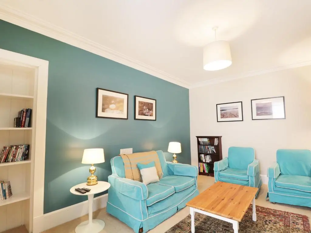 a living room with two blue chairs and a table at Annfield in Aberlour