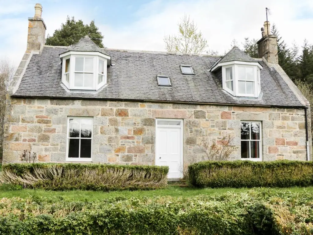 an old stone house with a white door and windows at Annfield in Aberlour