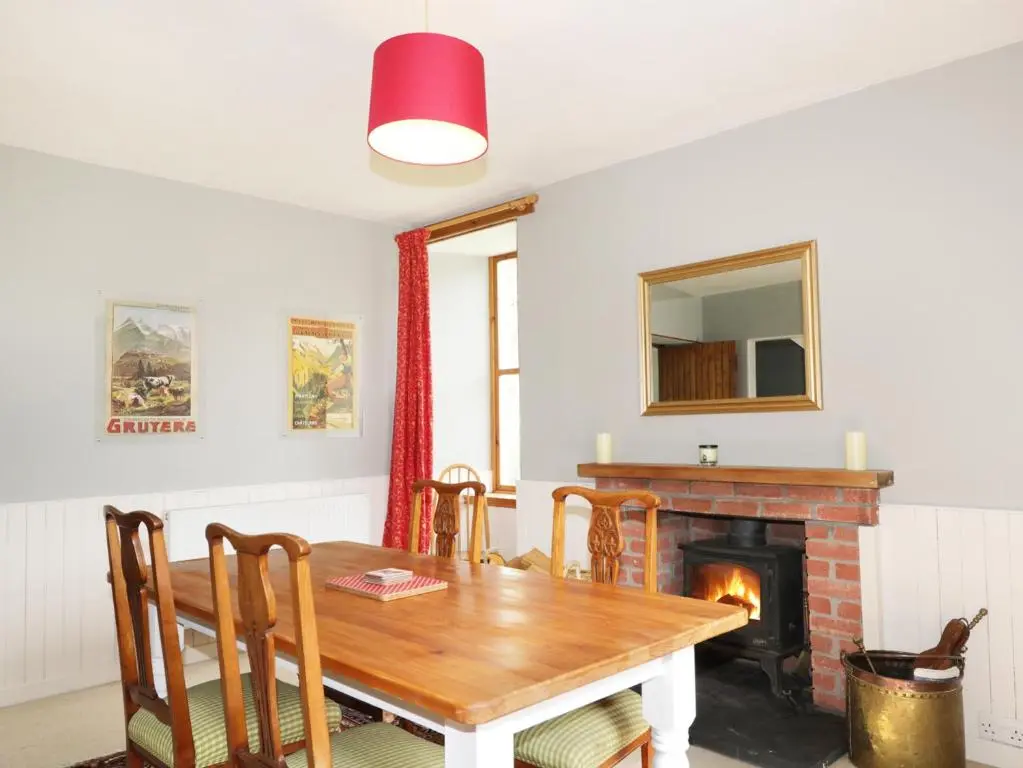 a dining room with a wooden table and a fireplace at Annfield in Aberlour