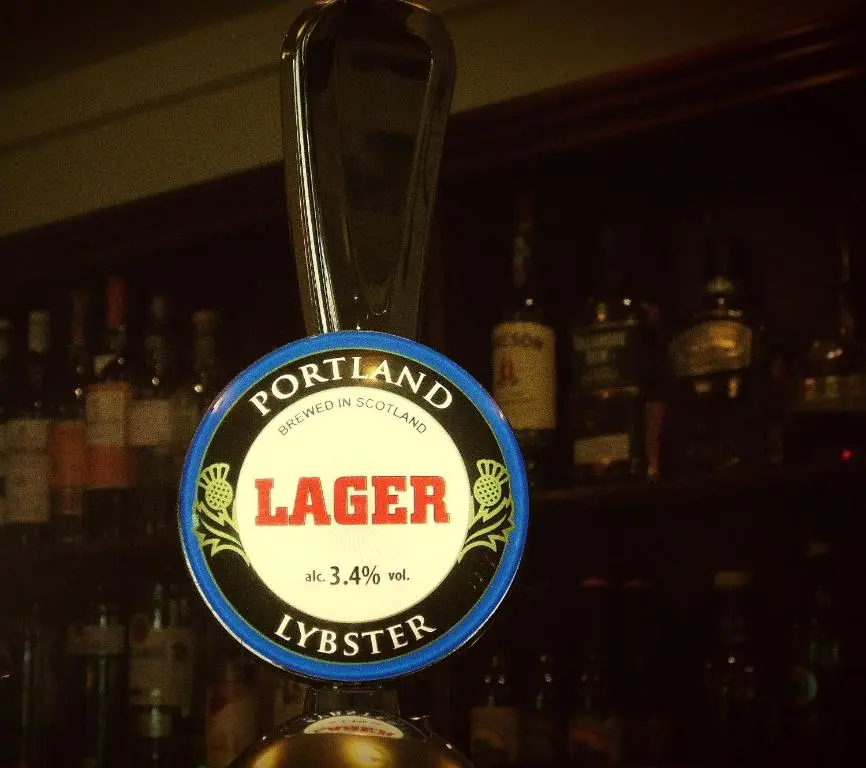 a bottle of liquor with a sign on a bar at The Portland Hotel in Lybster