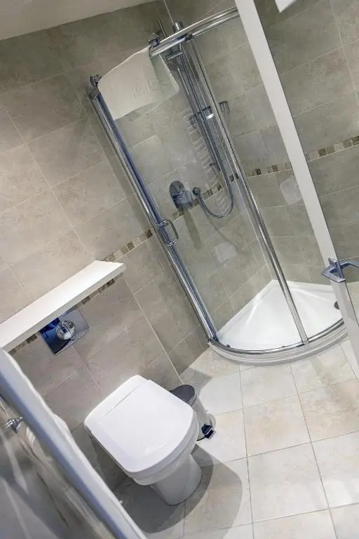 a bathroom with a shower and a toilet and a sink at The Portland Hotel in Lybster