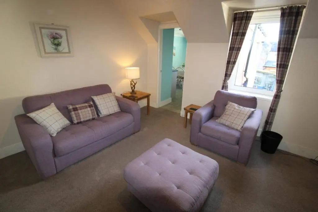 a living room with a couch and a chair and a ottoman at Easdale House Apartments in Inverness