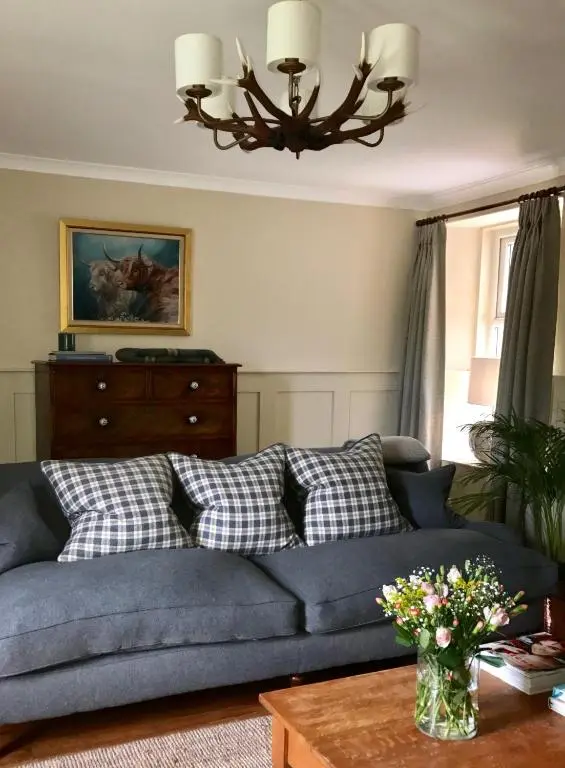 a living room with a blue couch and a table at Dandaleith Cottage No.2 in Craigellachie