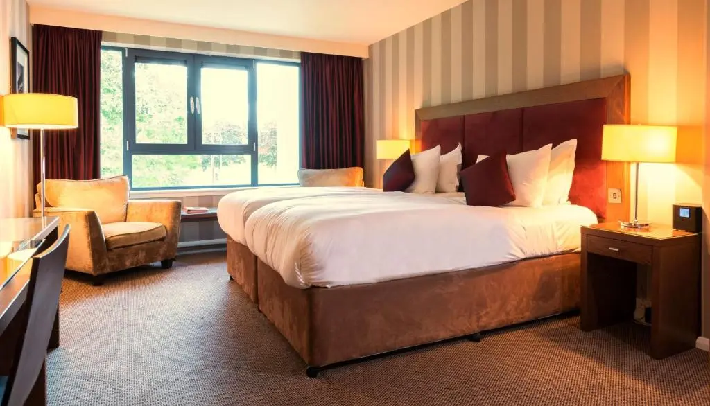 a hotel room with a large bed and a chair at Kingsmills Hotel in Inverness