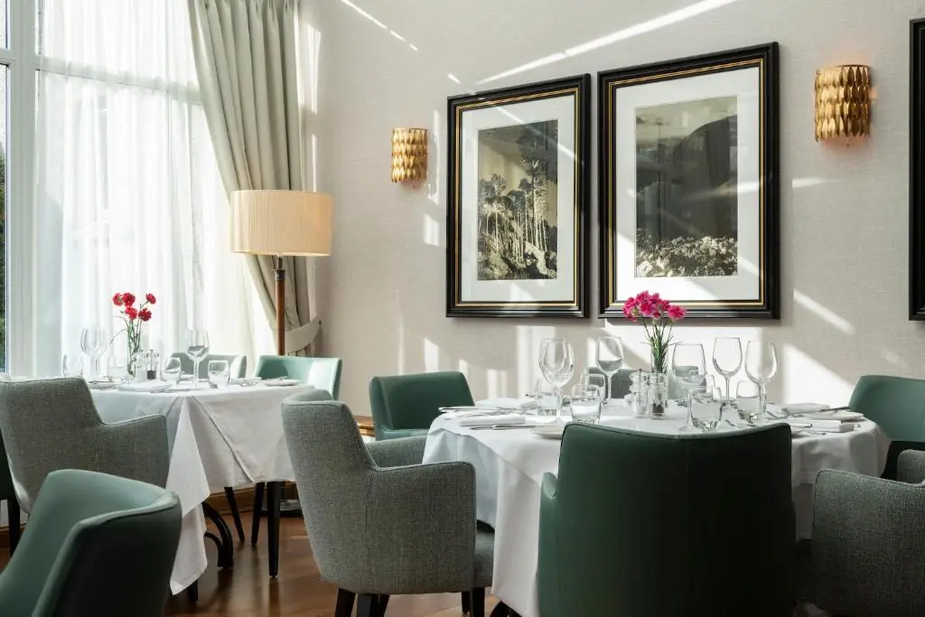 a dining room with white tables and green chairs at Kingsmills Hotel in Inverness