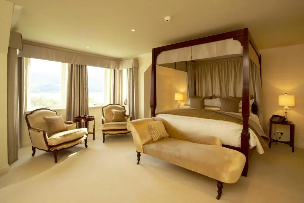 a bedroom with a large bed and a chair at Loch Ness Lodge in Drumnadrochit