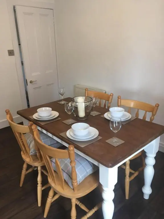 a wooden table with plates and wine glasses on it at Whisky Cottage in Inverness