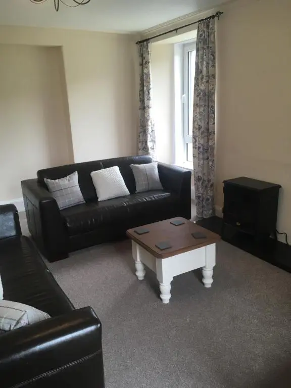 a living room with a black couch and a coffee table at Whisky Cottage in Inverness