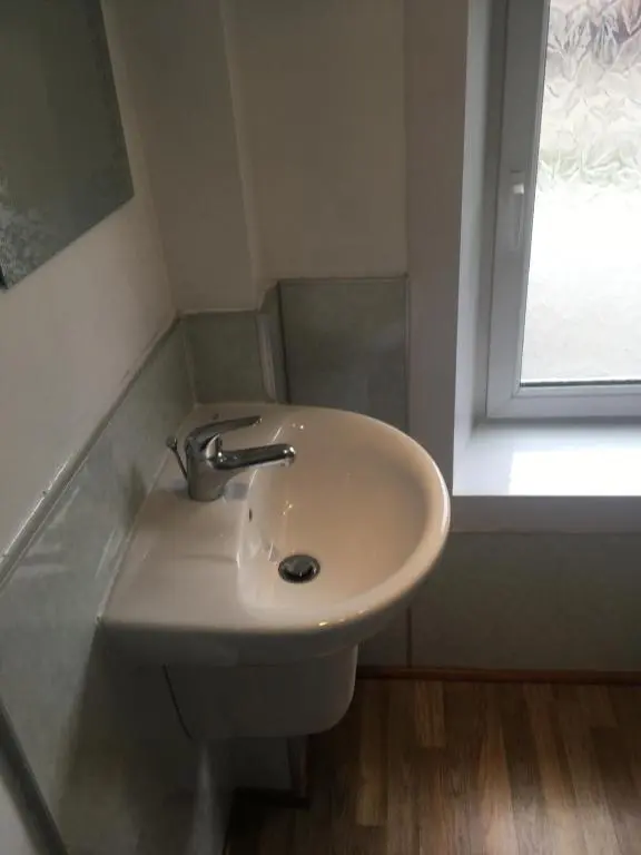 a white sink in a bathroom with a window at Whisky Cottage in Inverness