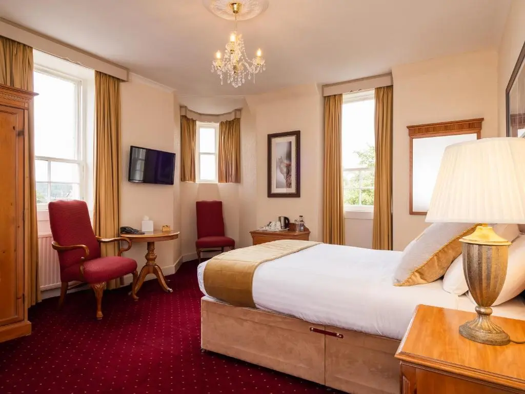 a hotel room with a bed and a chandelier at Grant Arms Hotel in Grantown on Spey