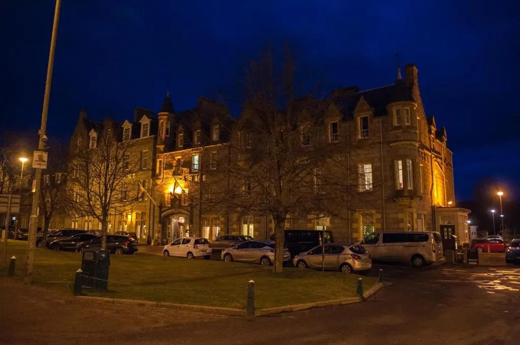 a building with cars parked in front of it at night at Grant Arms Hotel in Grantown on Spey