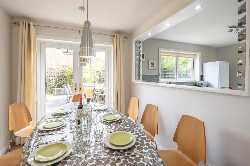 a dining room with a table and chairs and a mirror at White Corries in Aviemore