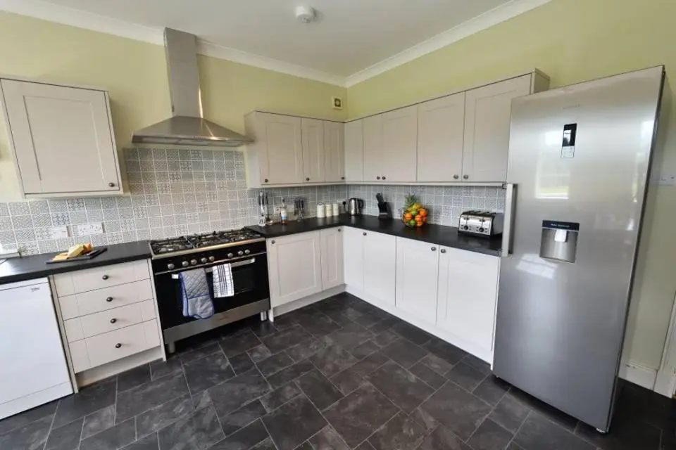 a kitchen with white cabinets and a refrigerator at Knocklea in Alness