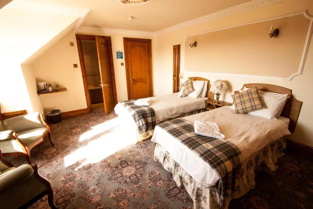 a hotel room with two beds and a chair at Duke Of Gordon Hotel in Kingussie