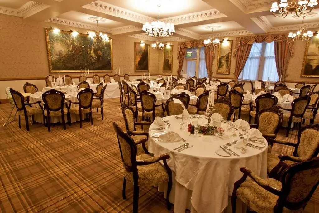 a banquet room with tables and chairs and a chandelier at Duke Of Gordon Hotel in Kingussie