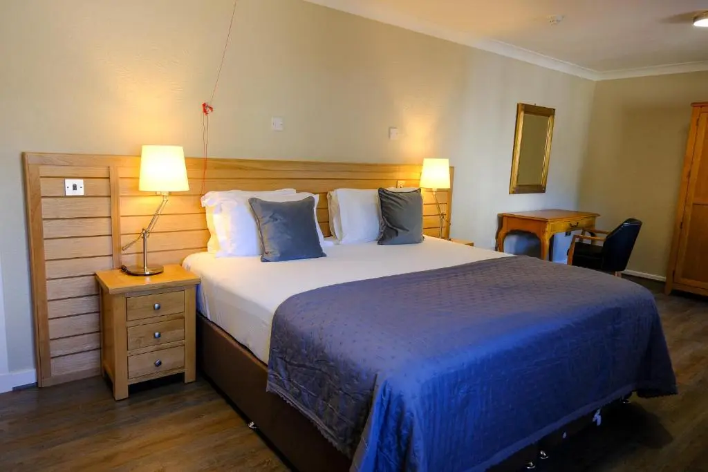 a bedroom with a large bed with blue sheets and pillows at Glen Mhor Hotel at Uile-bheist 'Brewstillery' in Inverness