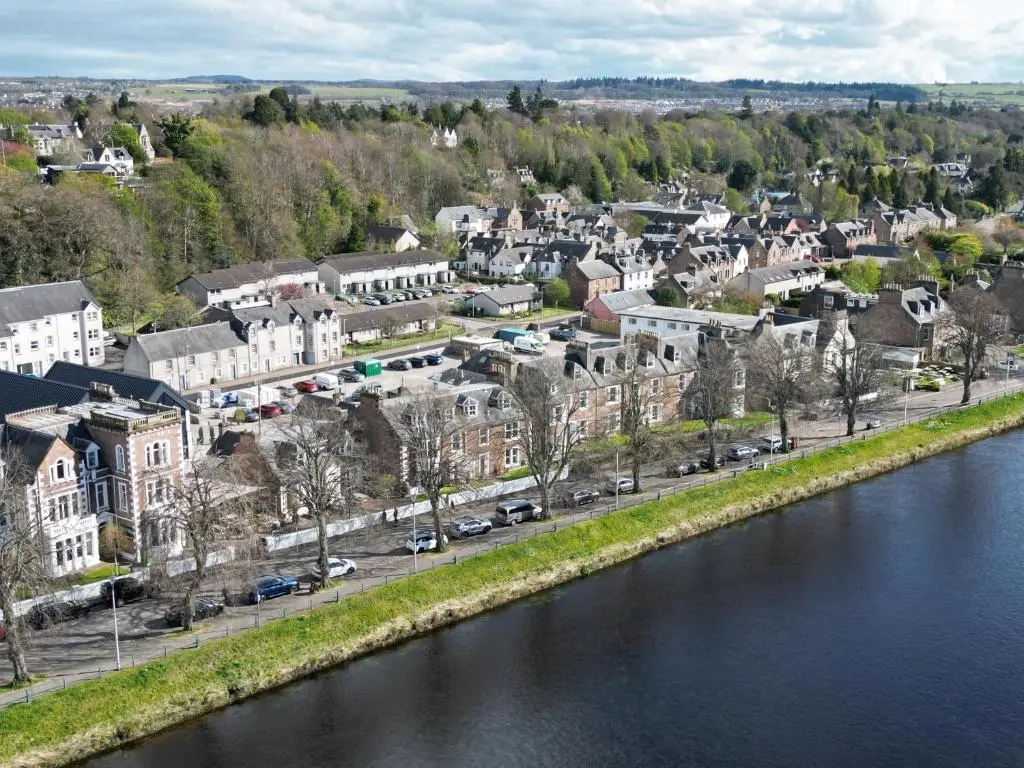 a town next to a river with buildings and cars at Glen Mhor Hotel at Uile-bheist 'Brewstillery' in Inverness