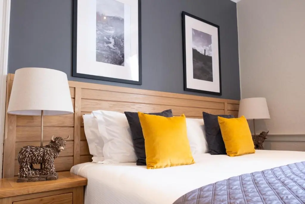 a bedroom with a bed with yellow pillows at Glen Mhor Hotel at Uile-bheist 'Brewstillery' in Inverness