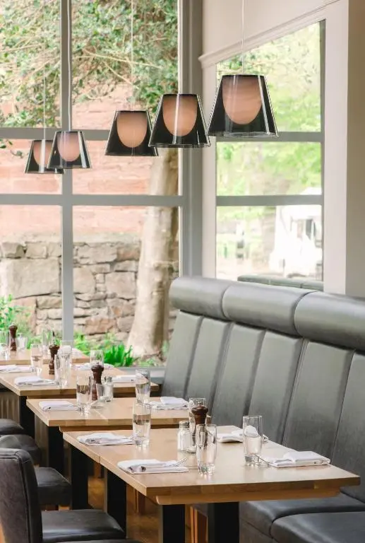 a row of tables in a restaurant with windows at Glen Mhor Hotel at Uile-bheist 'Brewstillery' in Inverness