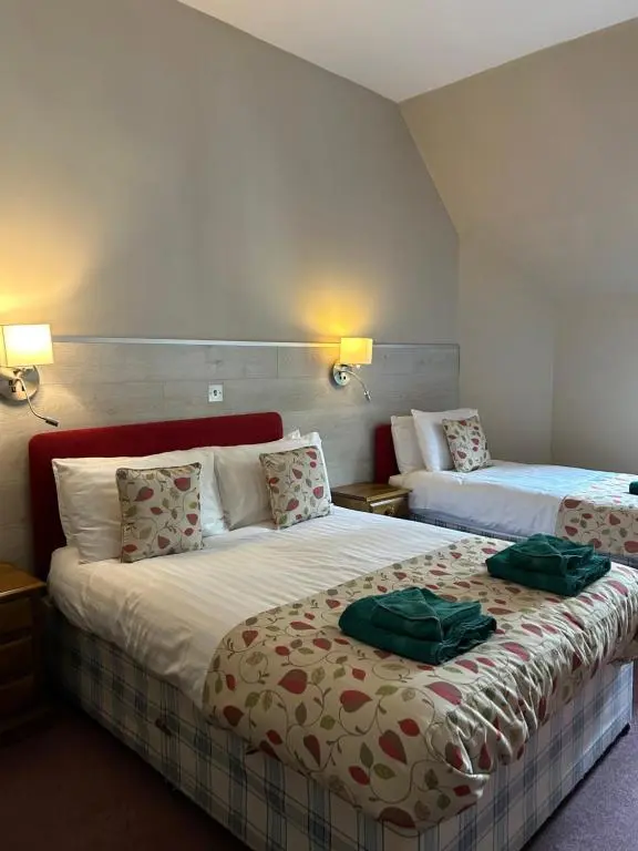 a hotel room with two beds with green towels on them at Fairburn Activity Centre in Contin