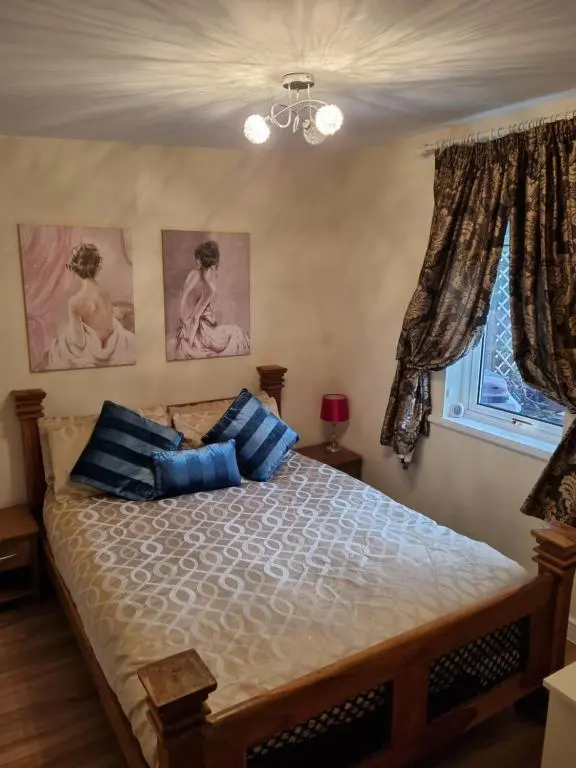 a bedroom with a bed with blue pillows and a window at Nanny's little highland hoose in Inverness