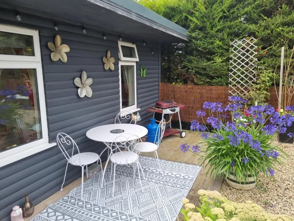 a patio with a table and chairs in front of a house at Nanny's little highland hoose in Inverness
