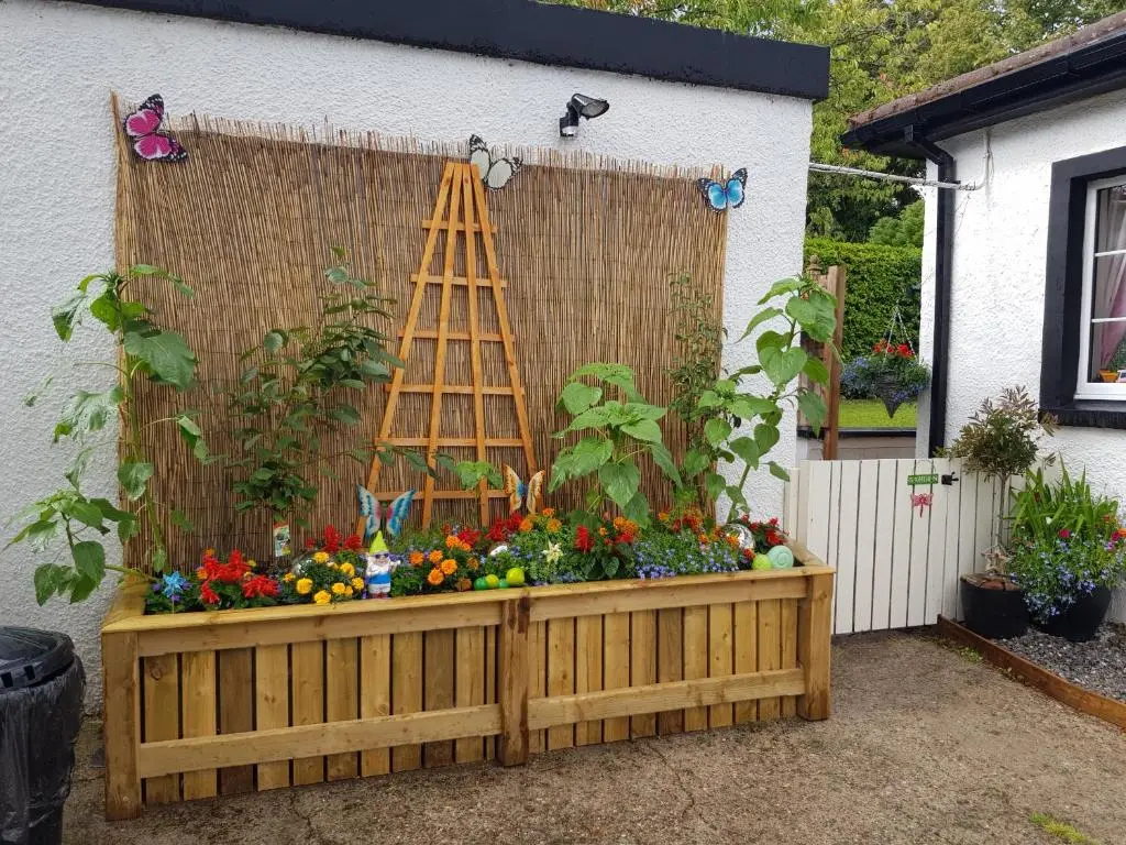 a garden with a ladder and flowers in a wooden box at Nanny's little highland hoose in Inverness