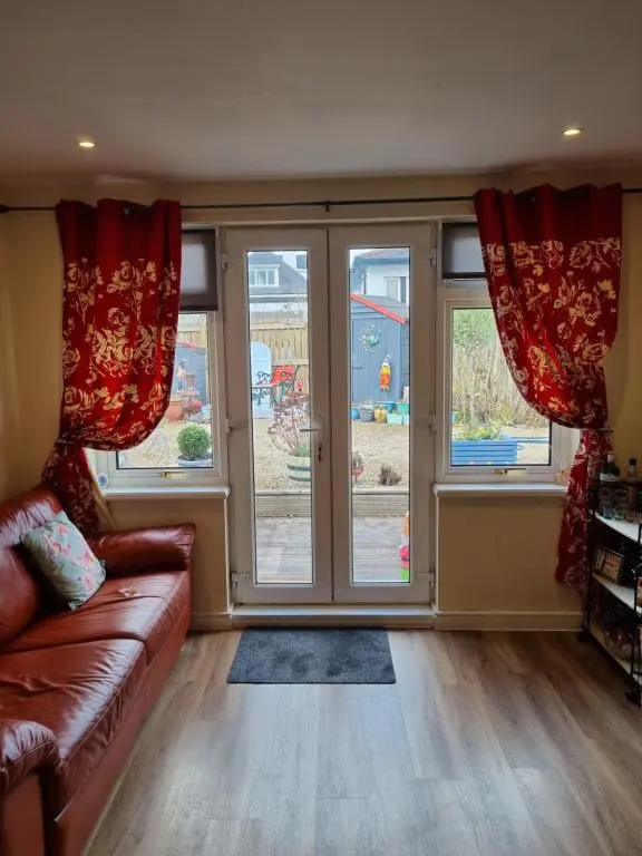 a living room with a couch and two windows at Nanny's little highland hoose in Inverness