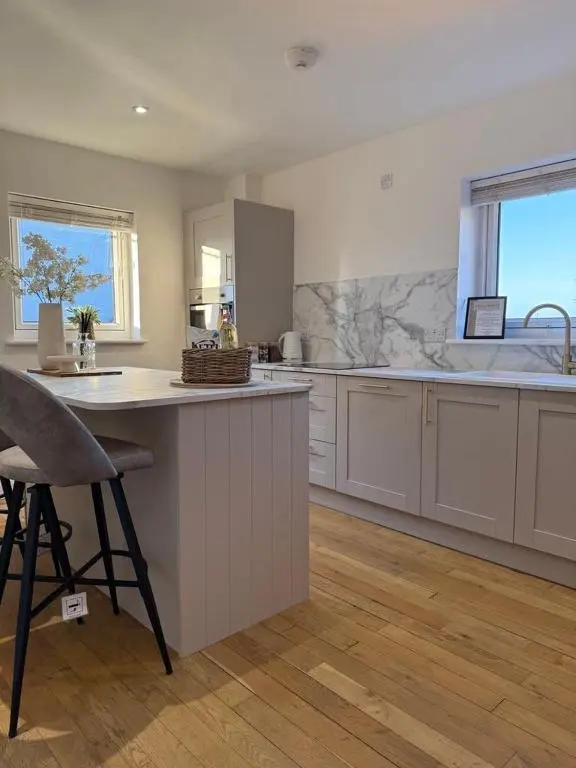 a large kitchen with white cabinets and a counter at Gateway Apartment in Inverness