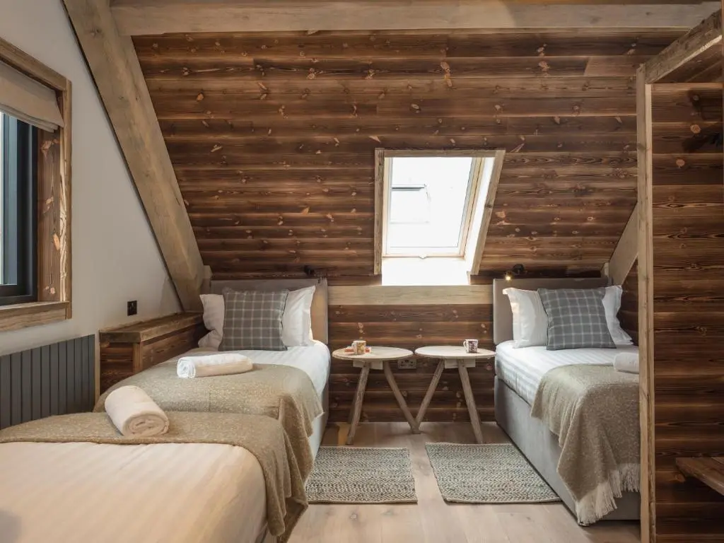 two beds in a room with wooden walls at Cairngorm Lodge in Aviemore