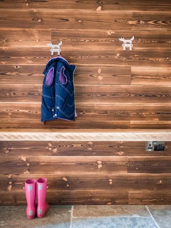 a pair of pink boots and a backpack on a wooden wall at Cairngorm Lodge in Aviemore