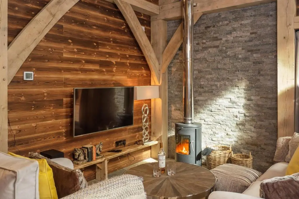 a living room with a tv and a wood wall at Macdui Lodge in Aviemore