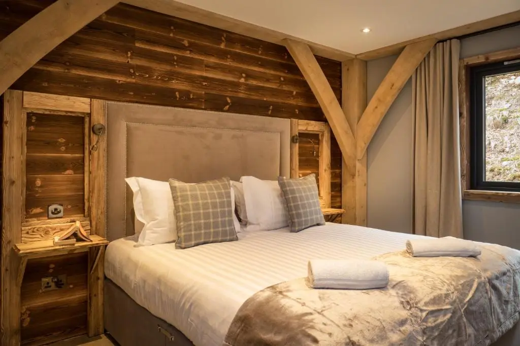 a bedroom with a large bed with a wooden wall at Macdui Lodge in Aviemore