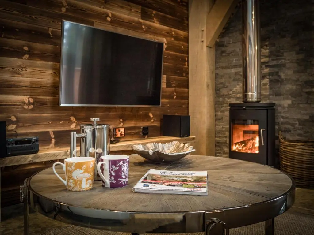 a table with two coffee cups and a television on a wall at Macdui Lodge in Aviemore