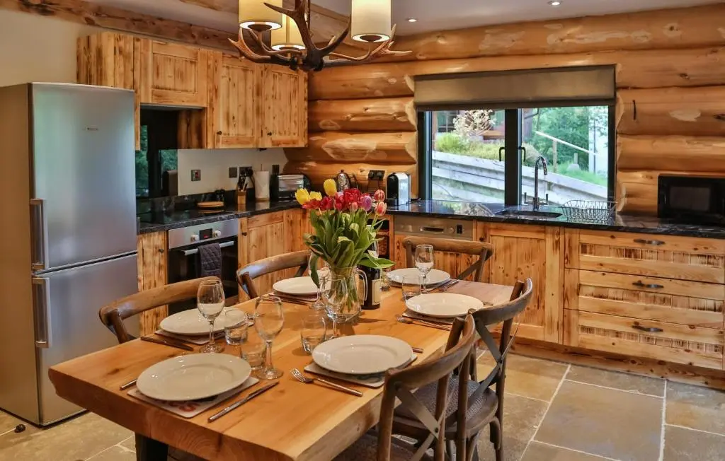 a kitchen with a wooden table with chairs and a refrigerator at Cedar Lodge in Aviemore