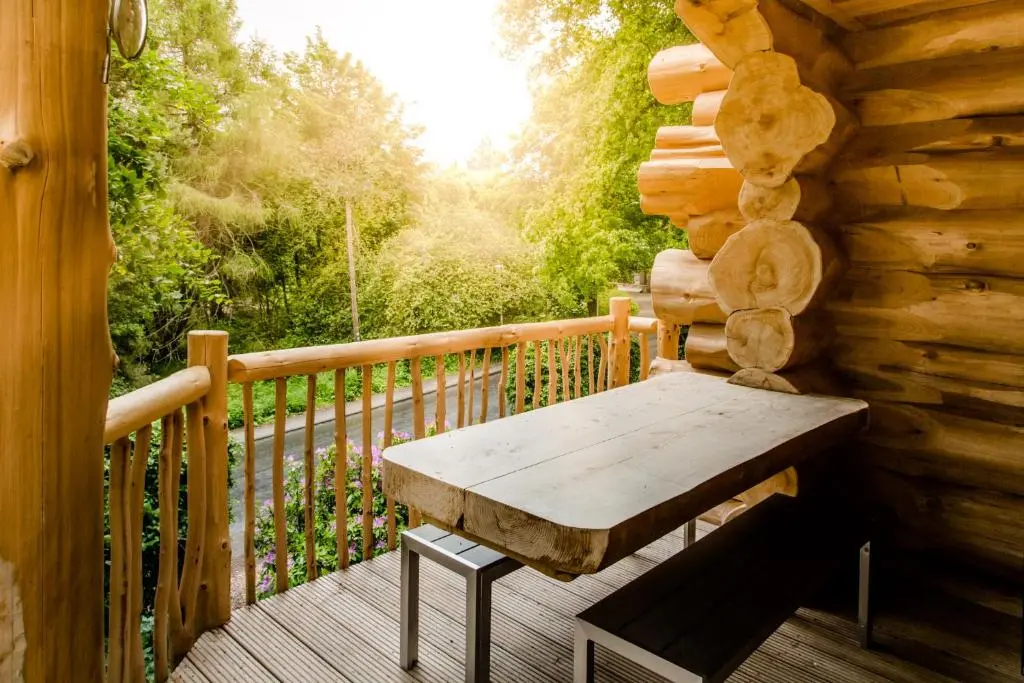 a wooden bench sitting on the deck of a cabin at Cedar Lodge in Aviemore
